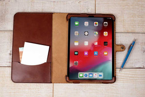 an ipad case with a notepad and pen next to it