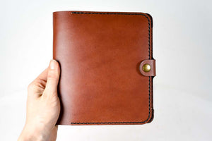 a hand holding a brown leather journal