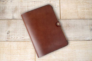 a brown leather notebook sitting on top of a wooden floor