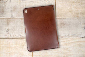a brown leather ipad case sitting on top of a wooden floor