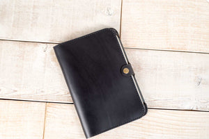 a black leather notebook sitting on top of a wooden floor