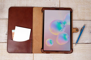 a tablet with a leather case and a notepad